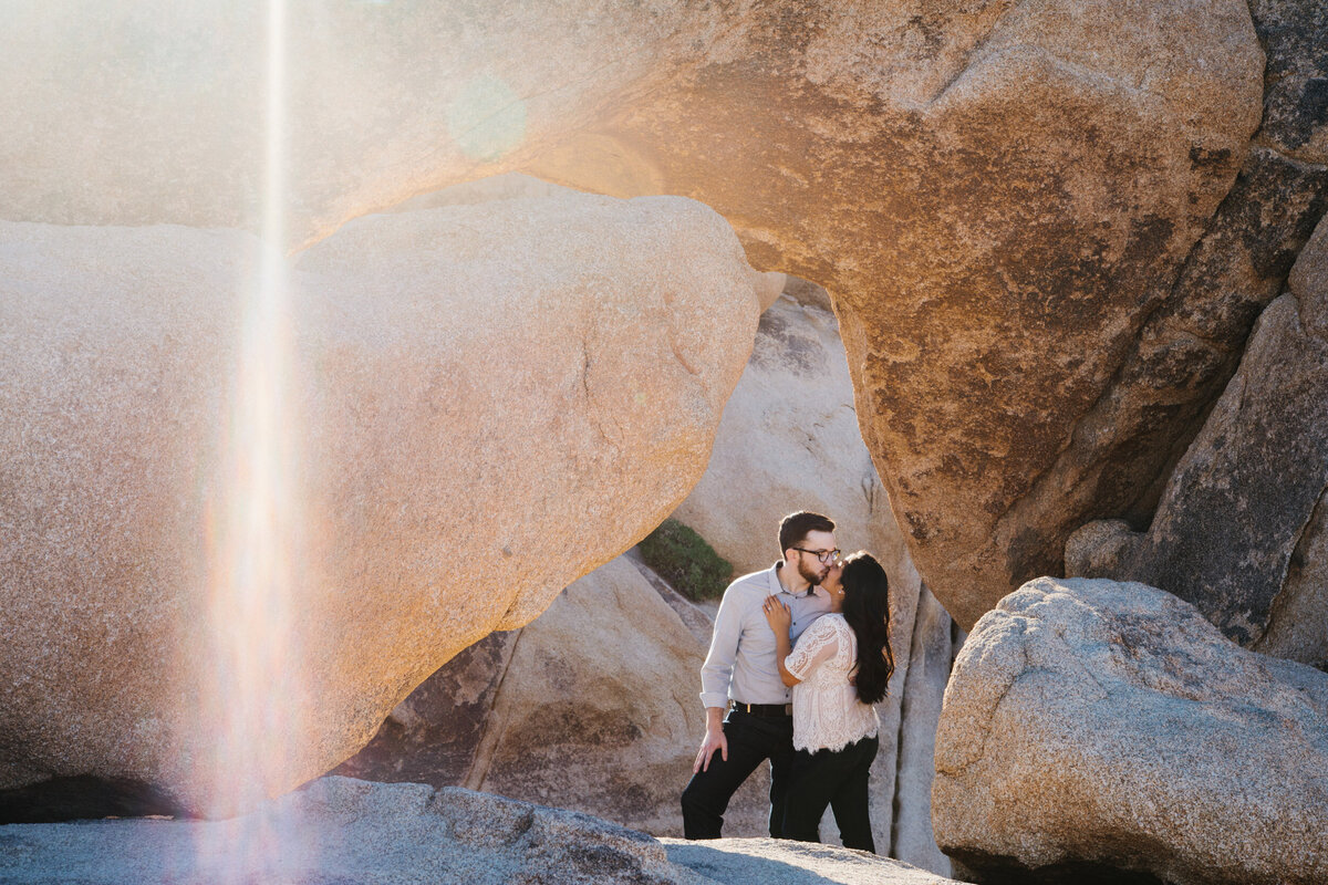 man and wife kiss under big rocks