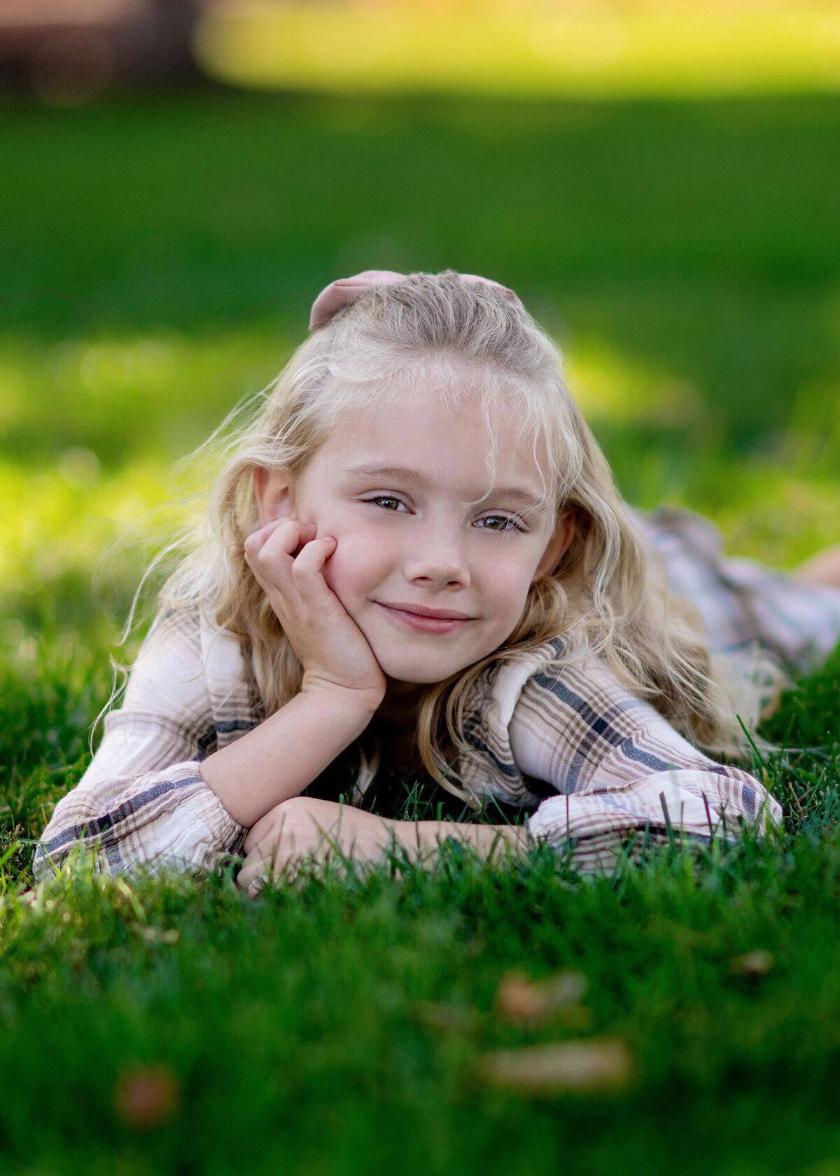 Little girl poses with her hand on her cheek in the grass