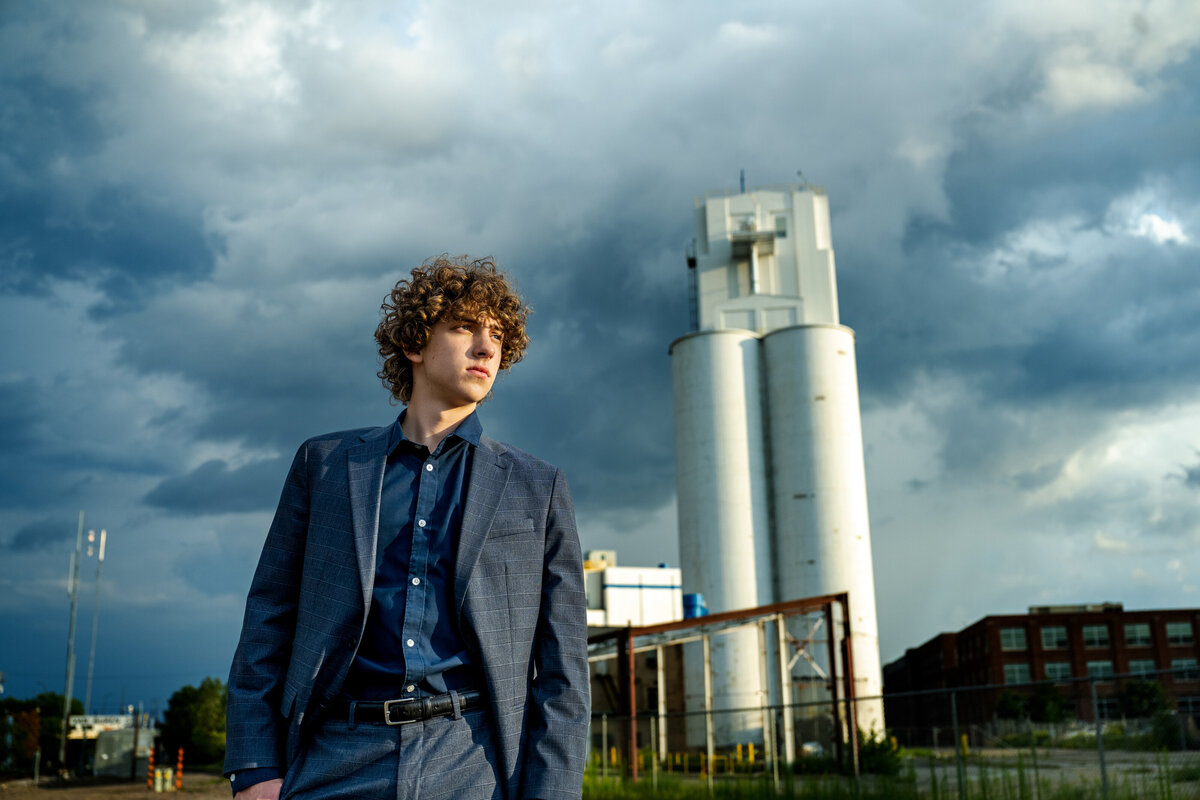 Wayzata Minnesota high school senior  photo of boy in suit in urban setting with dramatic skies