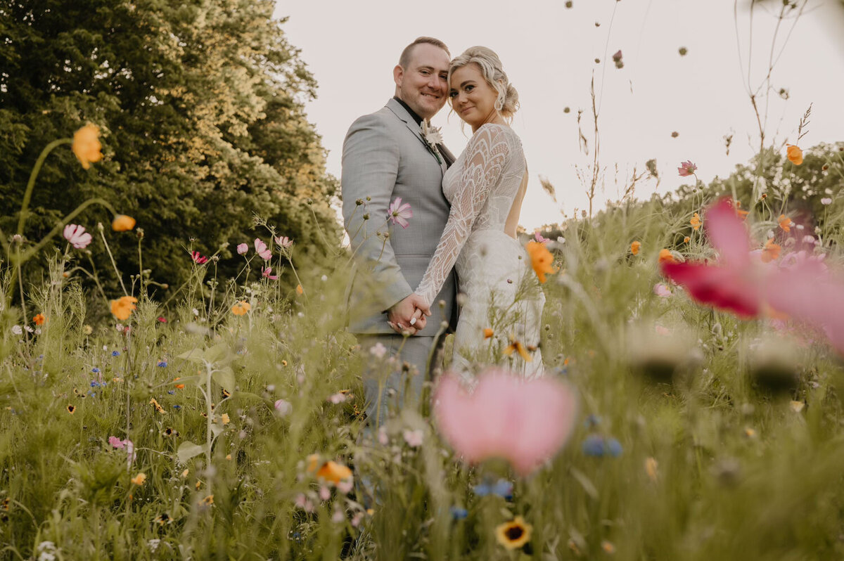 Bride and groom standing among wildflowers