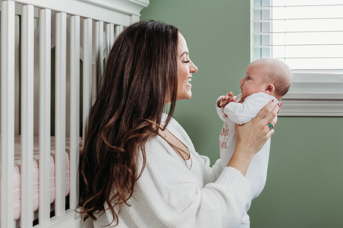Mom admiring her newborn girl during a family newborn photoshoot in Palatine, IL