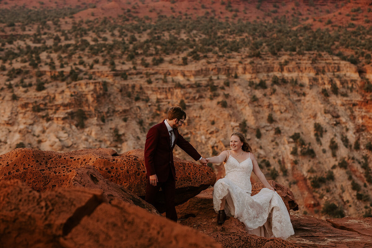 Bride and groom climbing on rocks during their elopement in Capitol Reef National Park