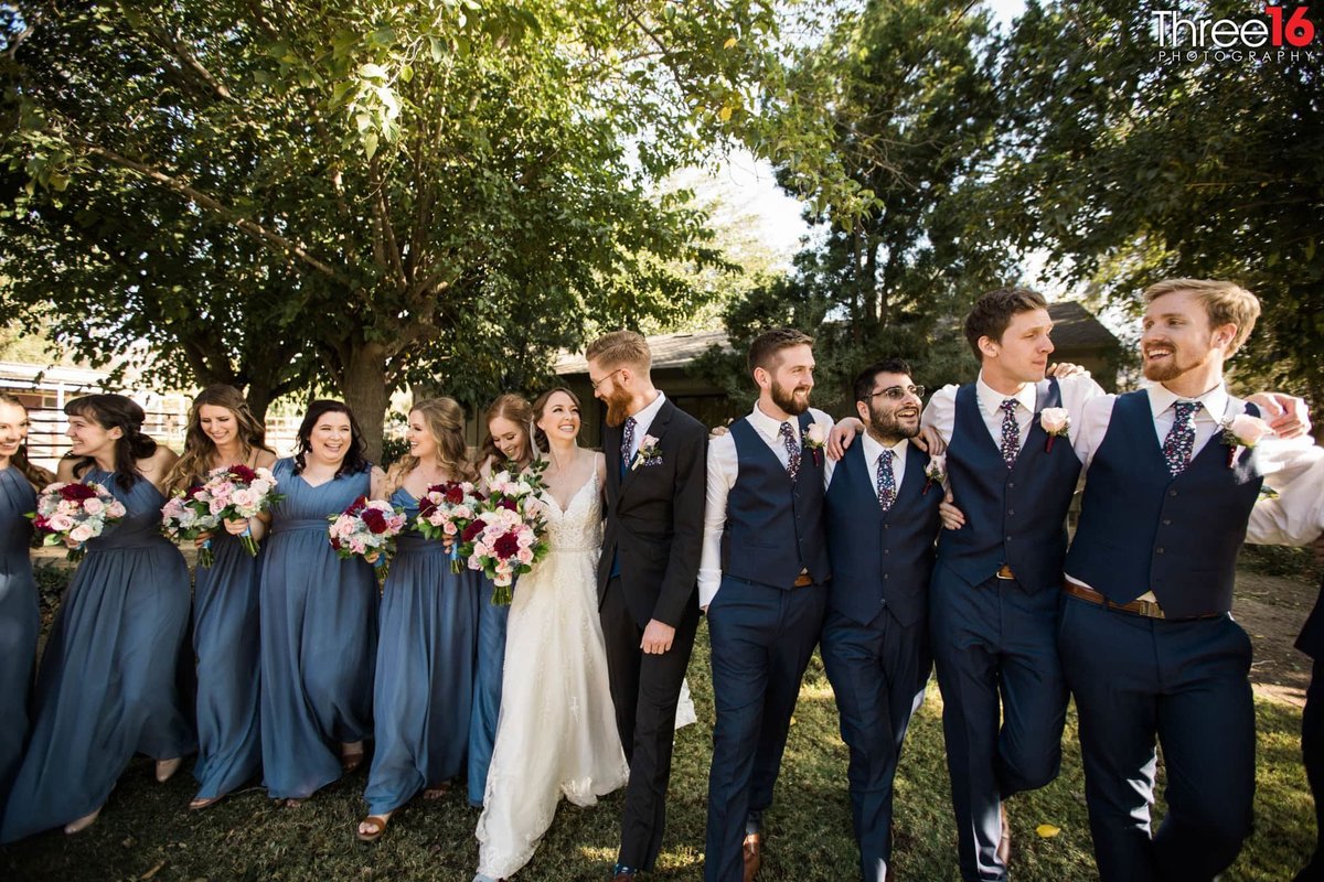 Bride and Groom laugh with each other as the bridal party have their own fun