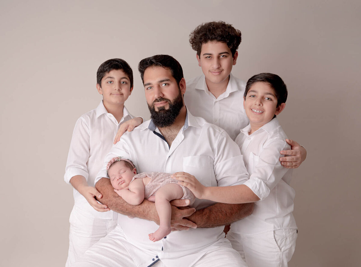 Father and siblings posing with a newborn for photoshoot in orlando