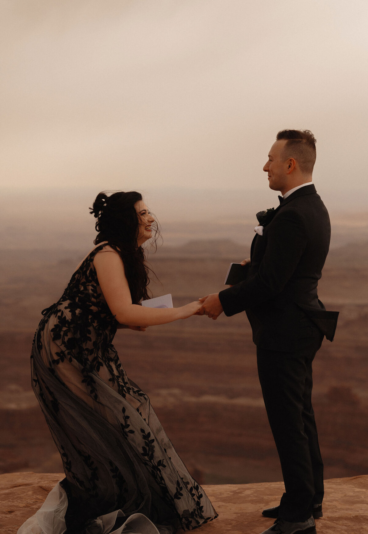 happy and excited couple holding hands while eloping with the Moab, Utah landscape in the background