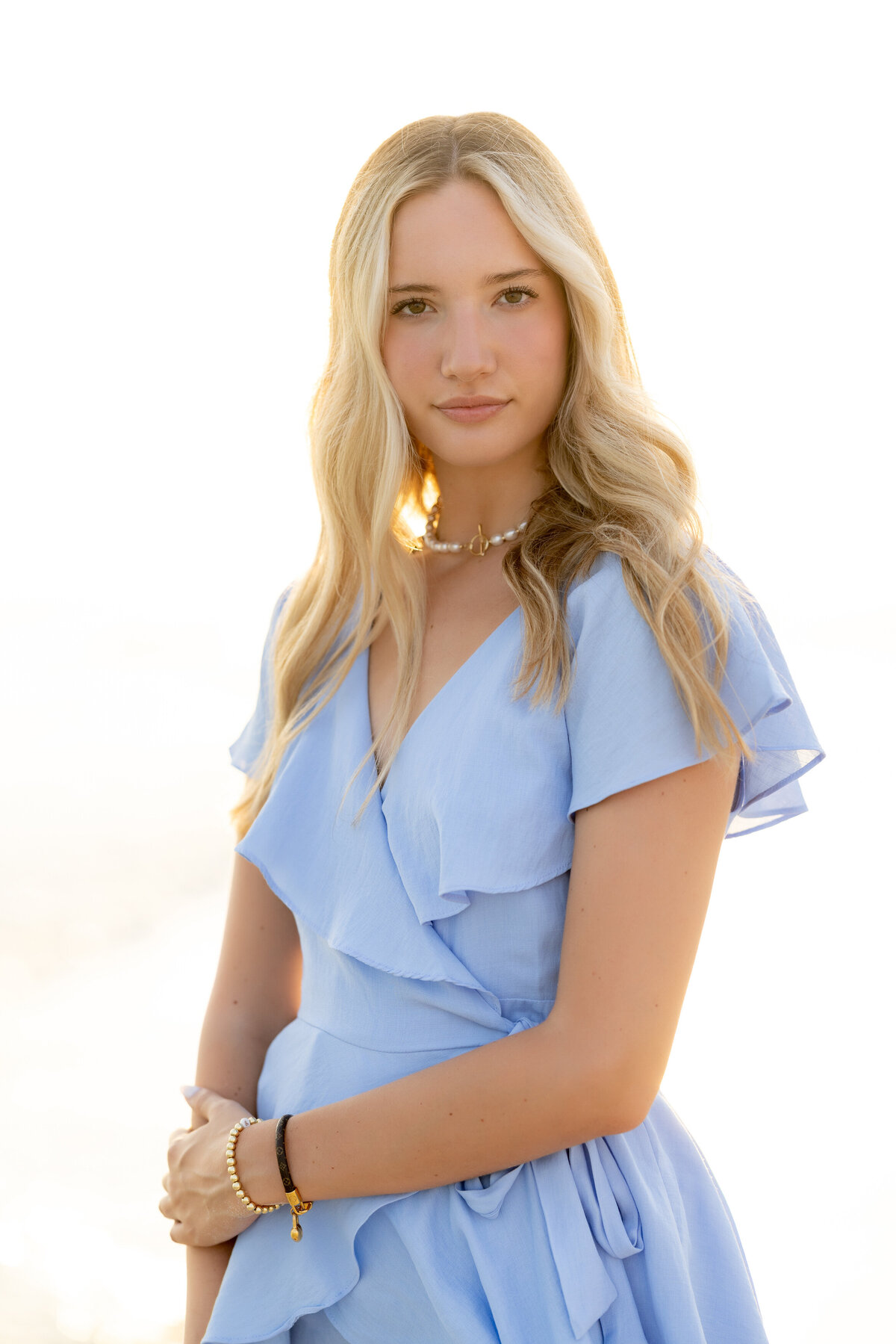 A girl in a blue dress with one arm wrapped around the other