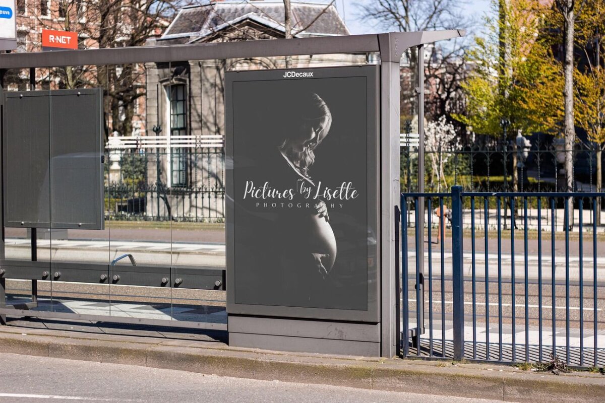 Outdoor bus stop advertisement display featuring a black-and-white maternity portrait of a pregnant woman in profile, with elegant script text “Pictures by Lisette Photography” across the image