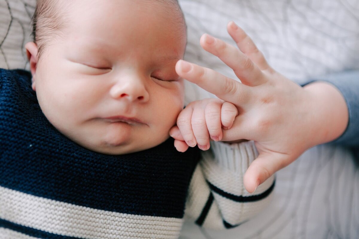 Baby holds onto sister's finger