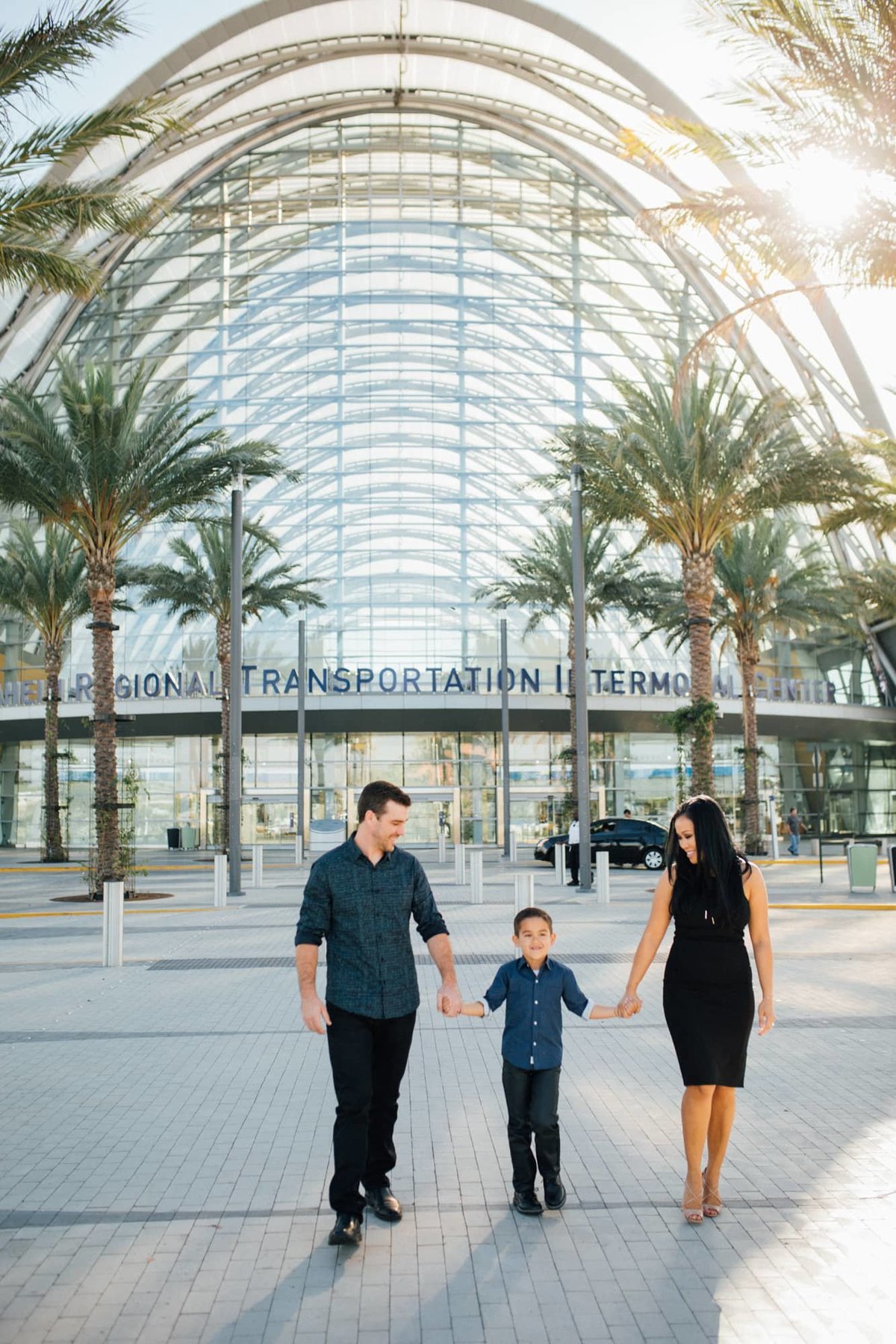 Mother and father hold hands with their young son as they walk away from the ARTIC Train Station in Anaheim