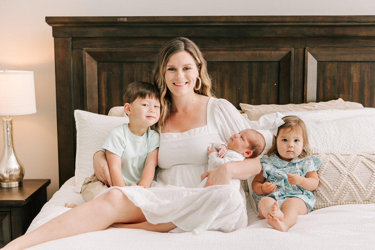 Mom and her three babies share a smile during their augusta ga newborn photography session