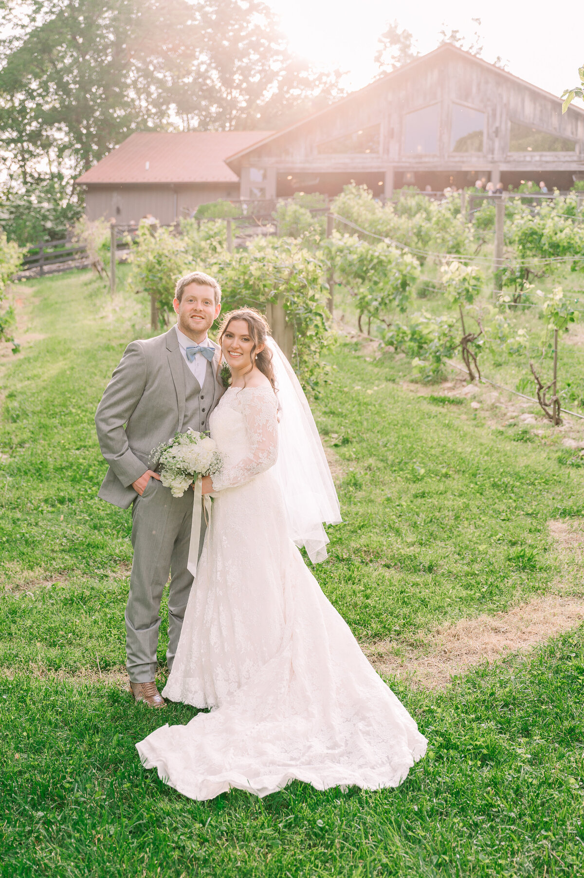 A loving couple during their portraits after their summer wedding ceremony in a luxurious green vineyard in the Blue Ridge Mountains by destination wedding photographer, JoLynn Photography