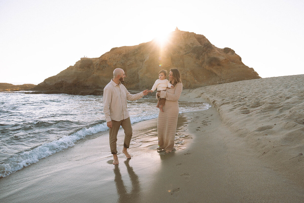 Family walking along the beach together at sunset, candid family photography session in Laguna Beach, California.