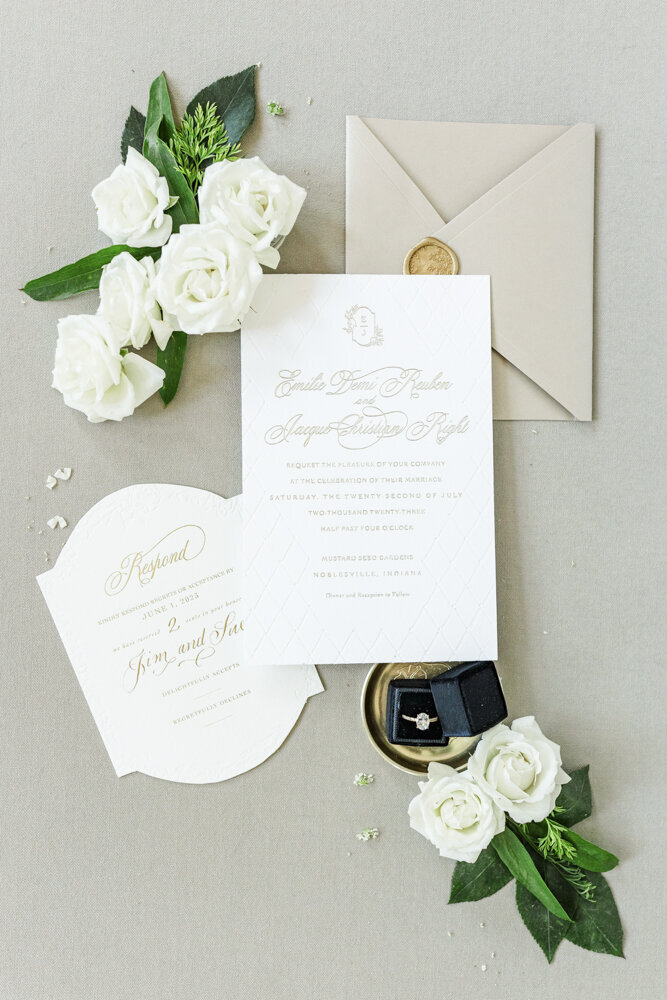 flat lay of white wedding invitation with white florals