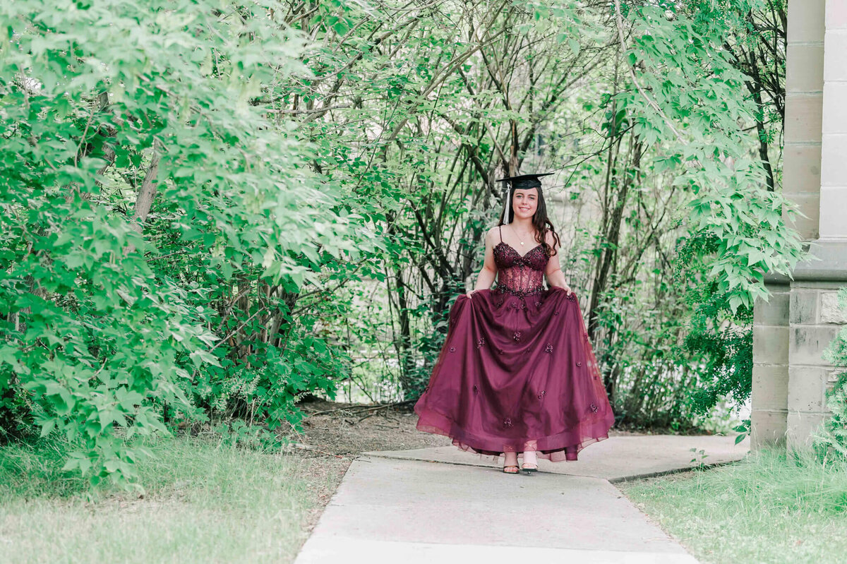 A brunette highschool grad walking forward.