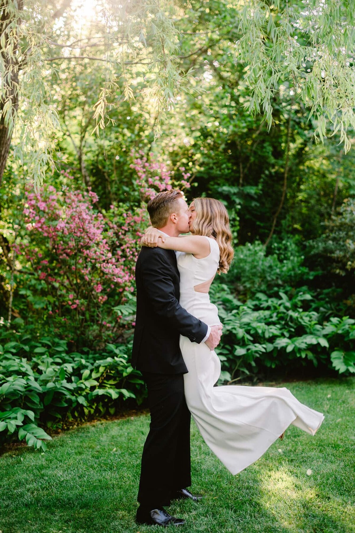 Groom lifts up bride for kiss in intimate gardens at Clifton Inn Charlottesville wedding