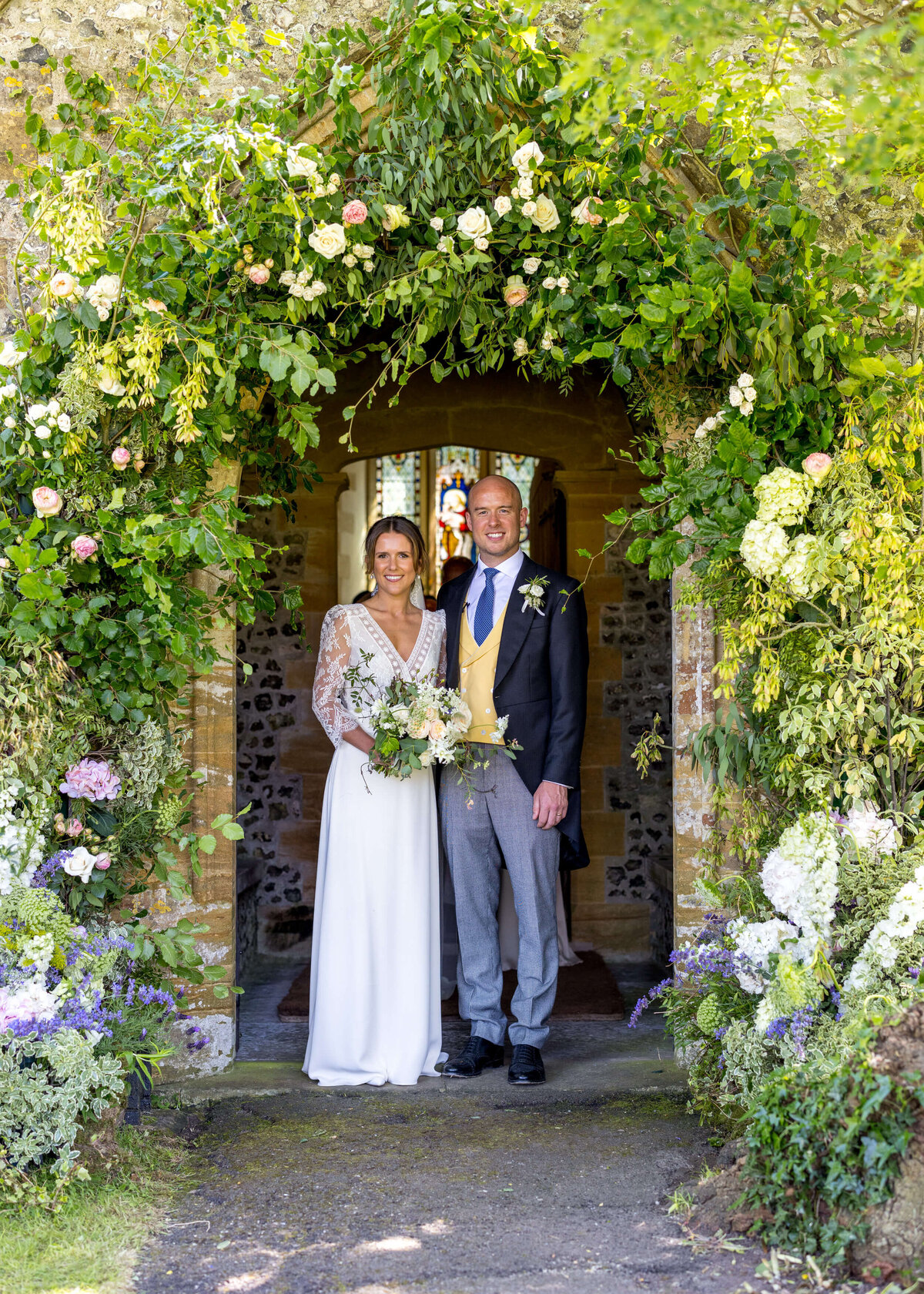 bride and groom under flower arch