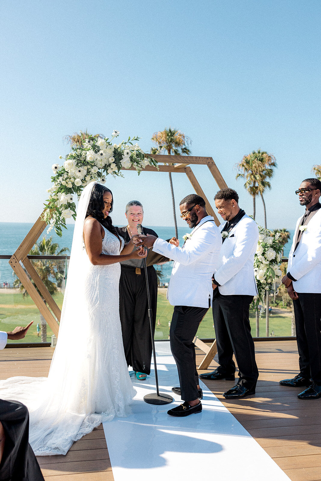 Bride and groom at the alter at their San Diego wedding with palm trees and the ocean in the background