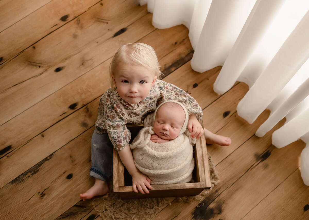 toddler sister hugging her baby brother