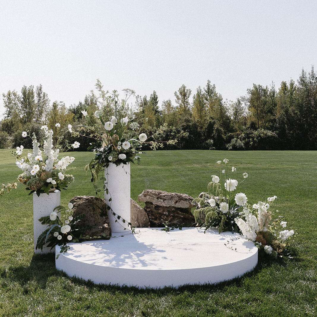 A set of staggered, organic ceremony arrangements of white flowers for an outdoor Montreal wedding.