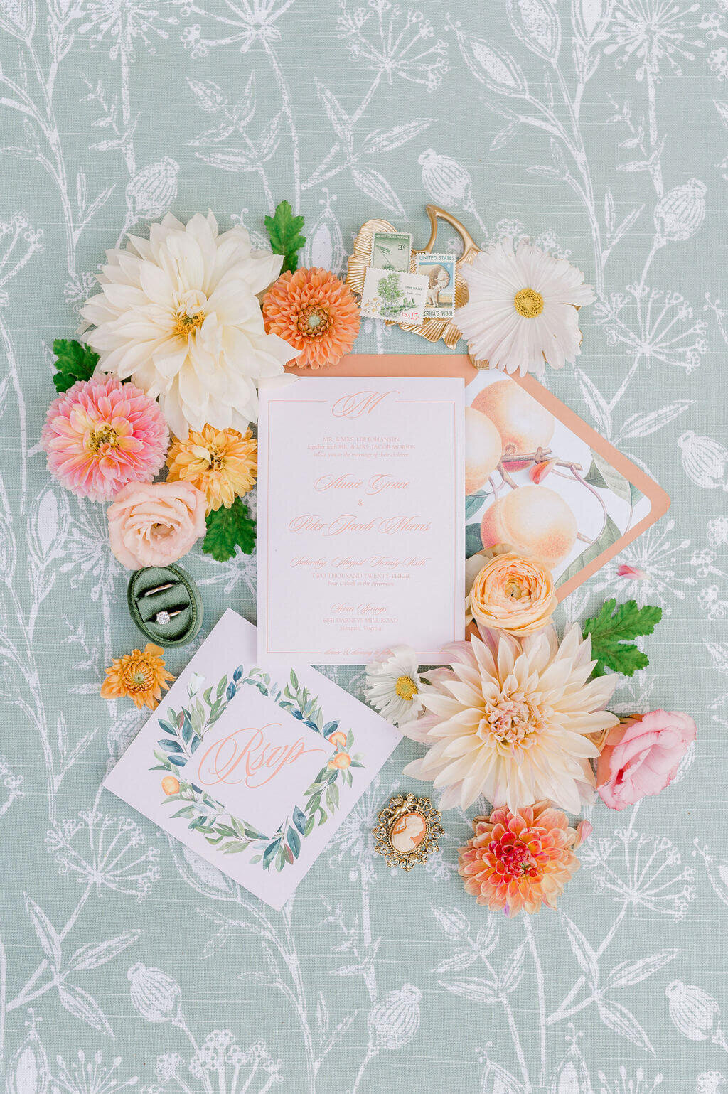 Elegant flat lay of peach-themed wedding stationery with custom crest, RSVP card, and floral accents. Includes keywords: wedding day stationery, luxury wedding invitations, wedding stationery, wedding invitation designer.