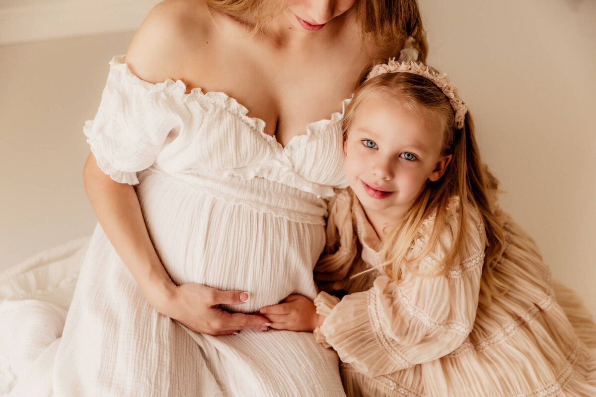 Girl with blue eyes near her pregnant mother's baby bump.
