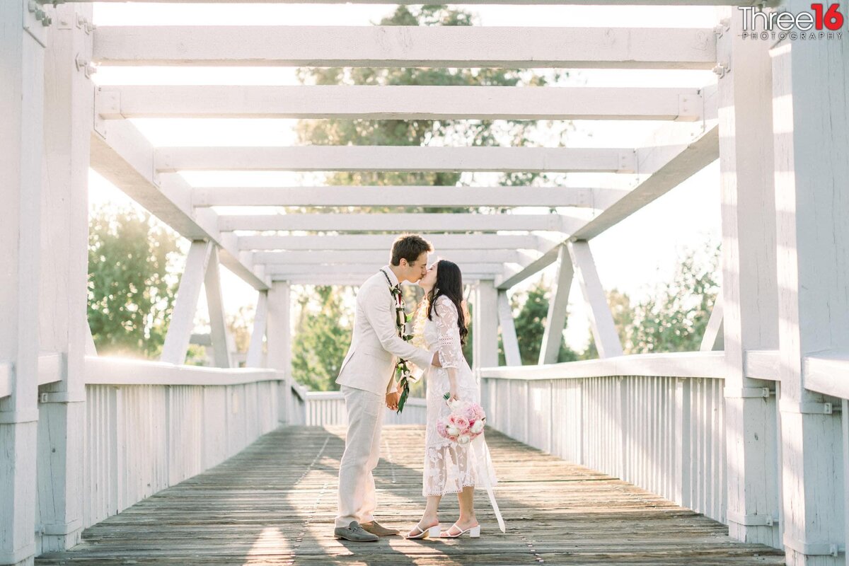 Engaged couple sharing a kiss on a bridge during engagement session