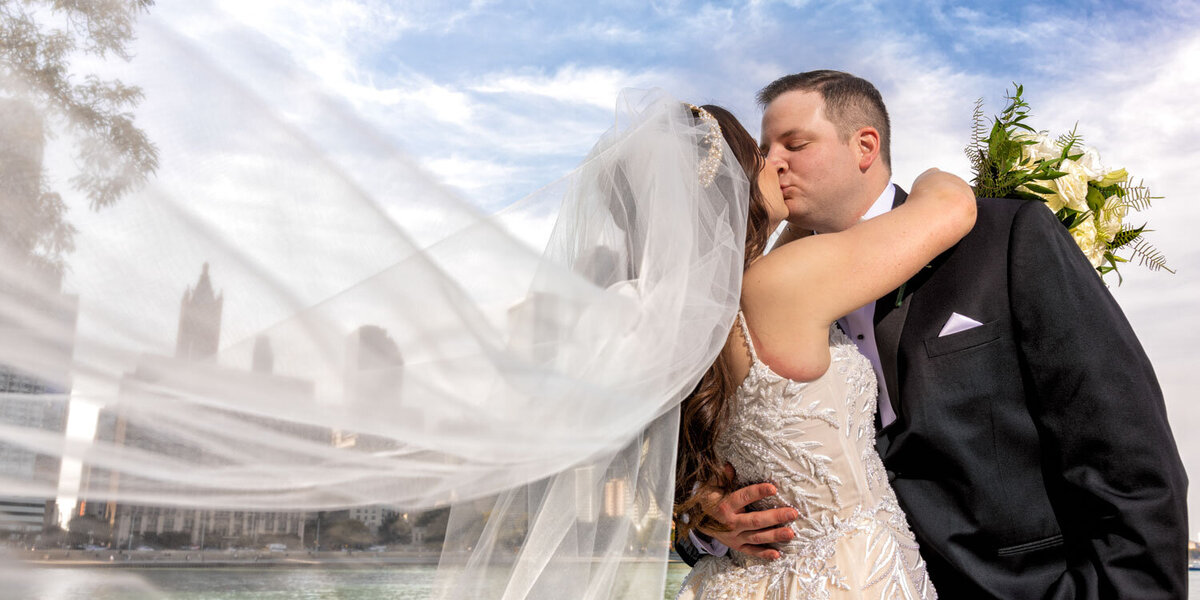 A bride and groom kissing under a veil