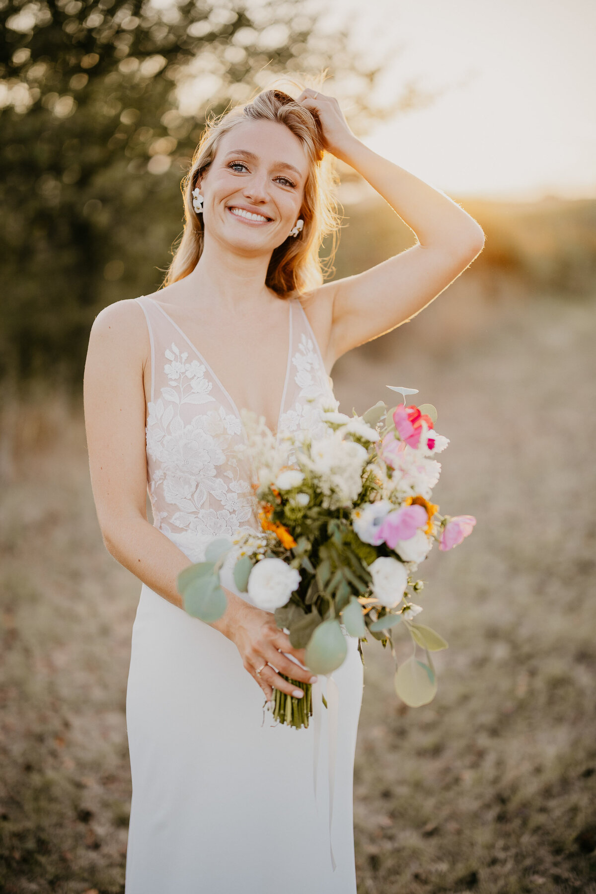 Smiling bride with colorful bouquet in the fields of Borgo Divino, wedding photographer Tuscany.