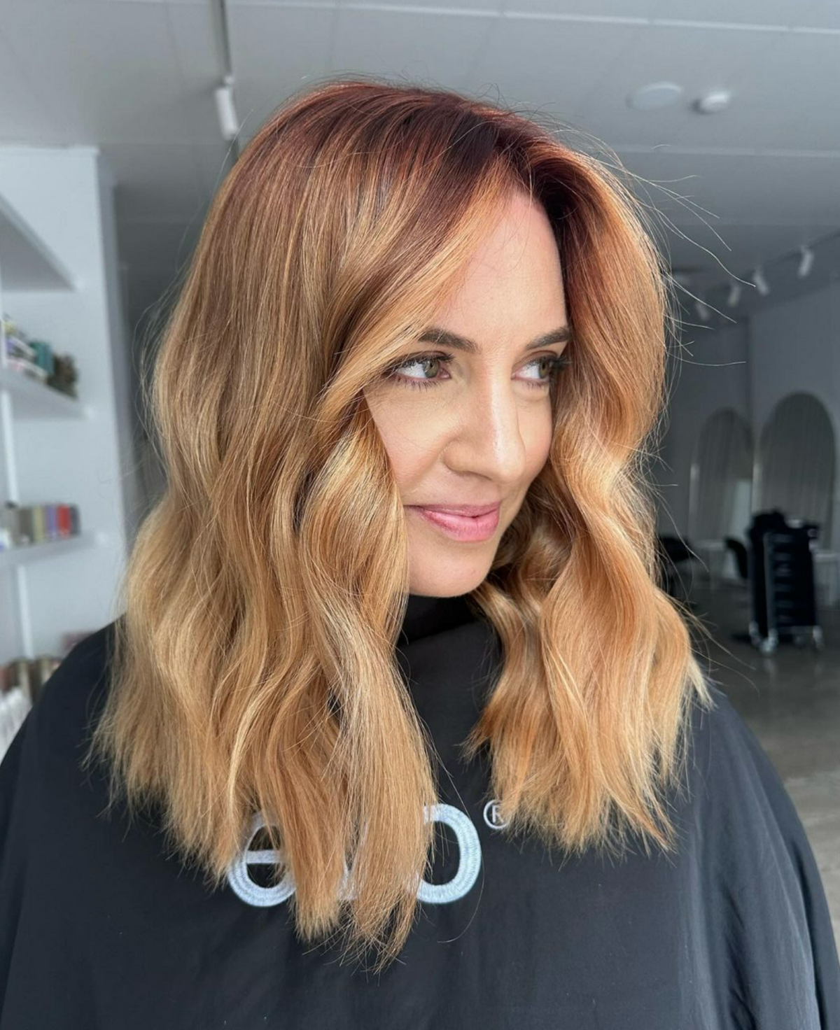 Woman I black hairdresser cape with freshly coloured hair - copper