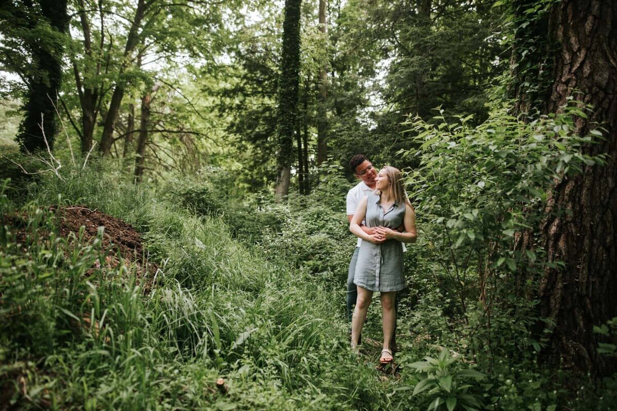 Couple hugging in forest surrounded by greenery. in New York