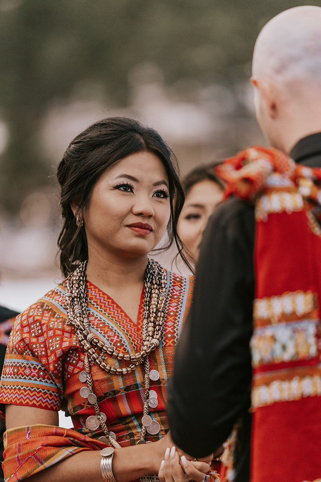 Bride lovingly looks at her groom during their wedding ceremony wearing red.