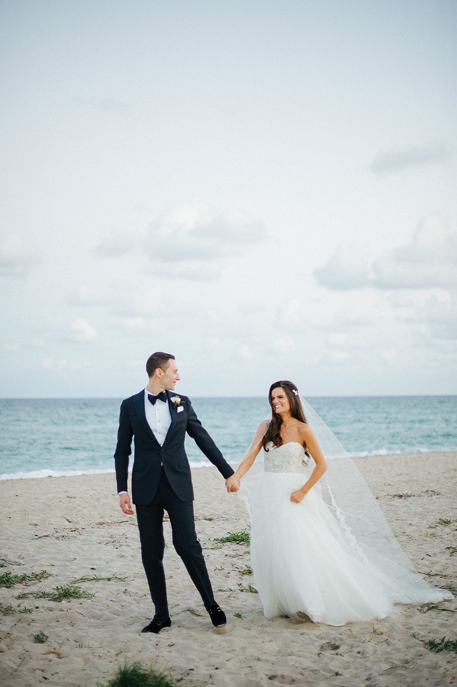 couple holding hands walking on palm beach