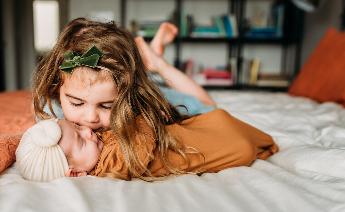Newborn Photographer, Big sister kissing little sister on the cheek.