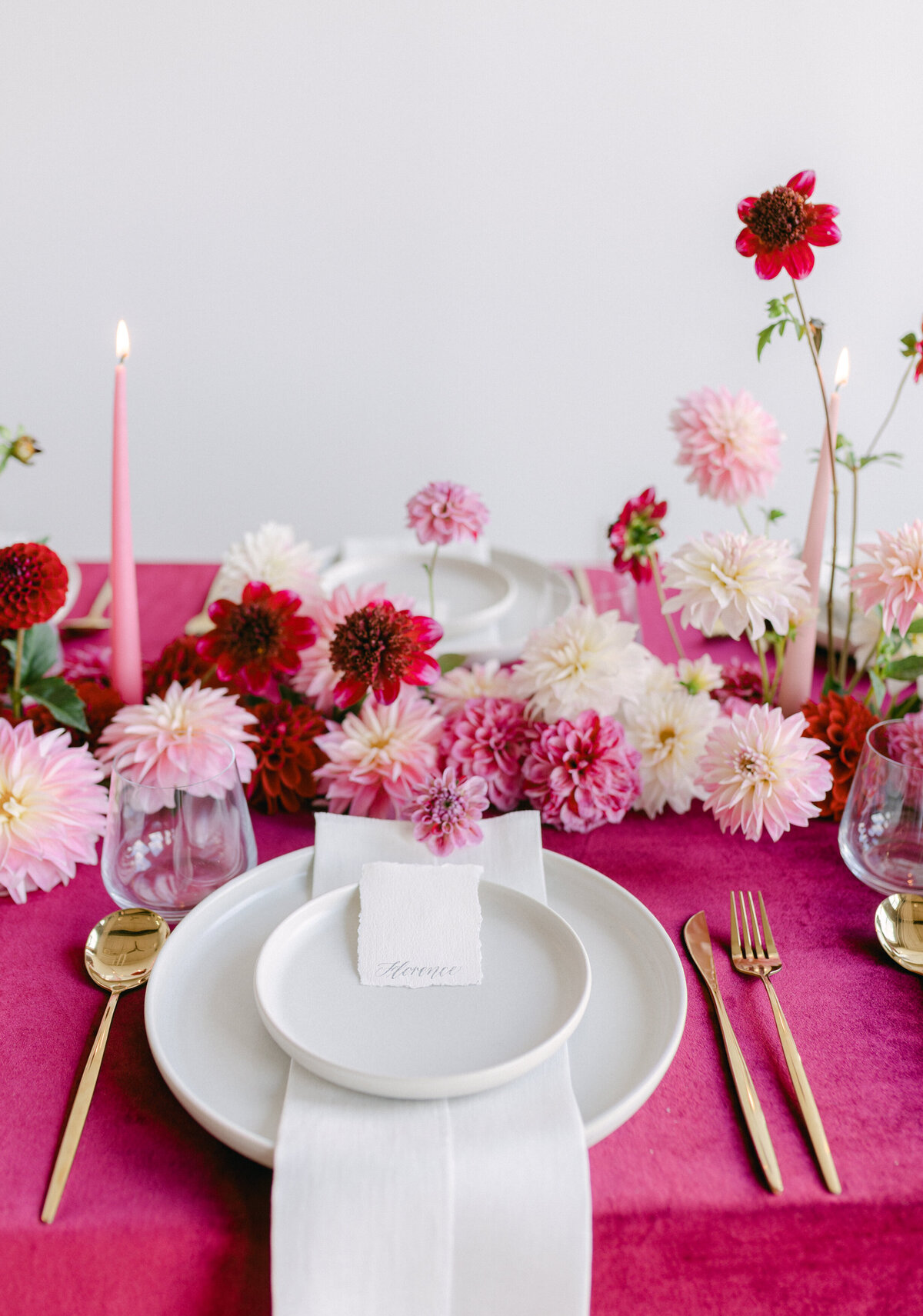 A centrepiece of bold pink and red flowers on a table with a bright tablecloth.