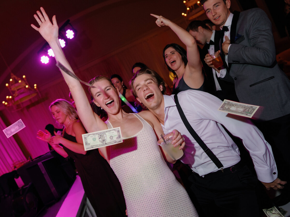 Bride and groom throwing money on the dance floor during wedding reception