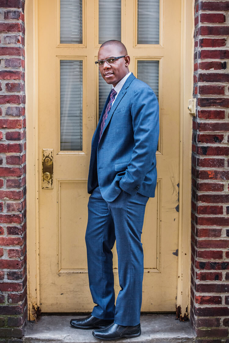 A person in a suit leaning up against a door