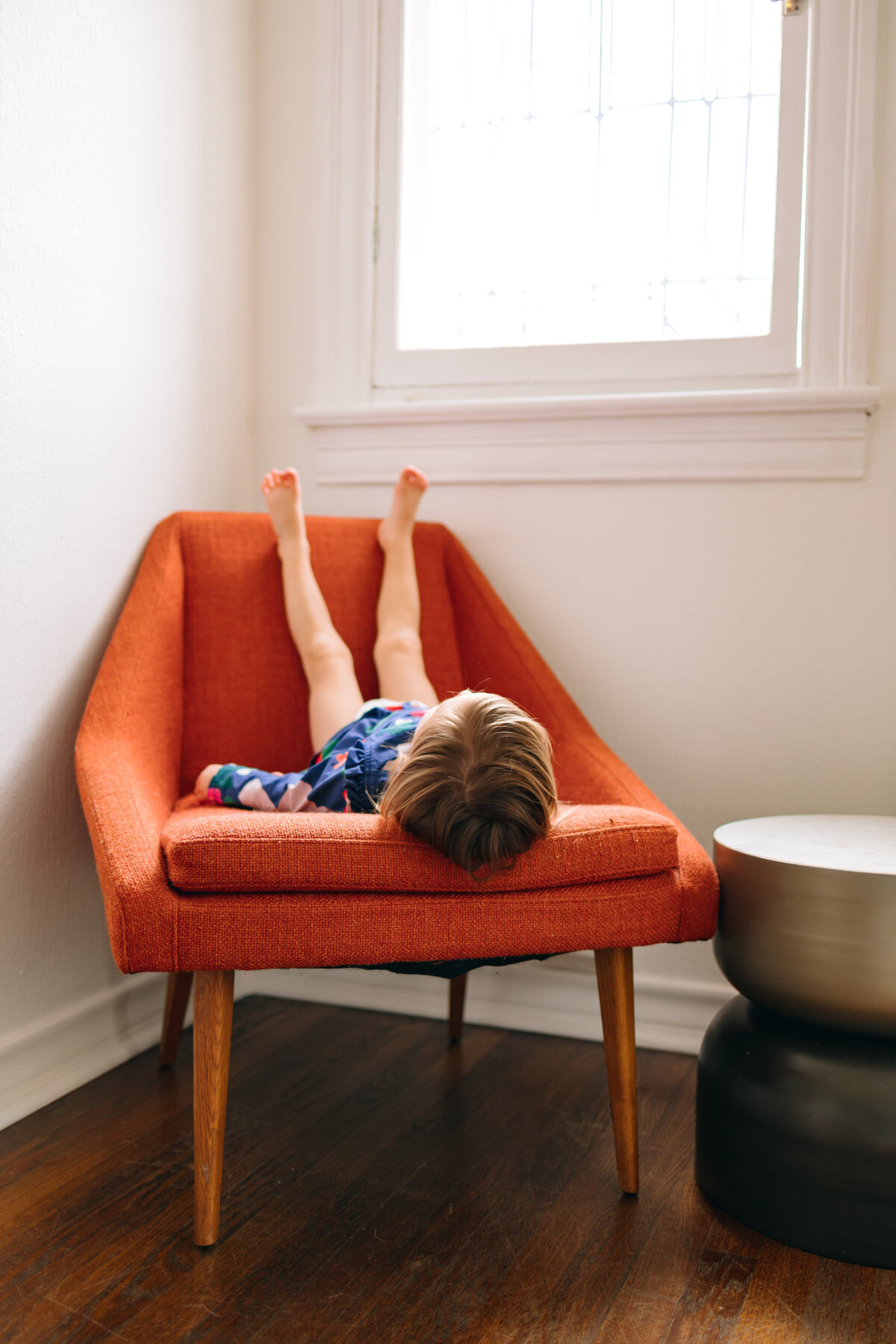 A heartwarming moment captured by an Albuquerque family photographer. The little boy, dressed in comfortable blue and red pajamas, is playing with a red chair in a beautiful house. This image highlights the joy and comfort of home.