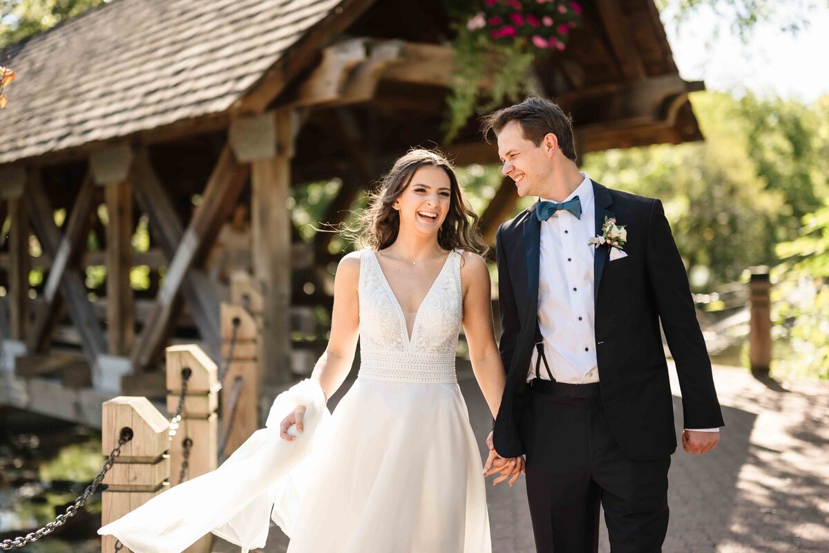 Bride and groom walk in front of a bridge in Naperville