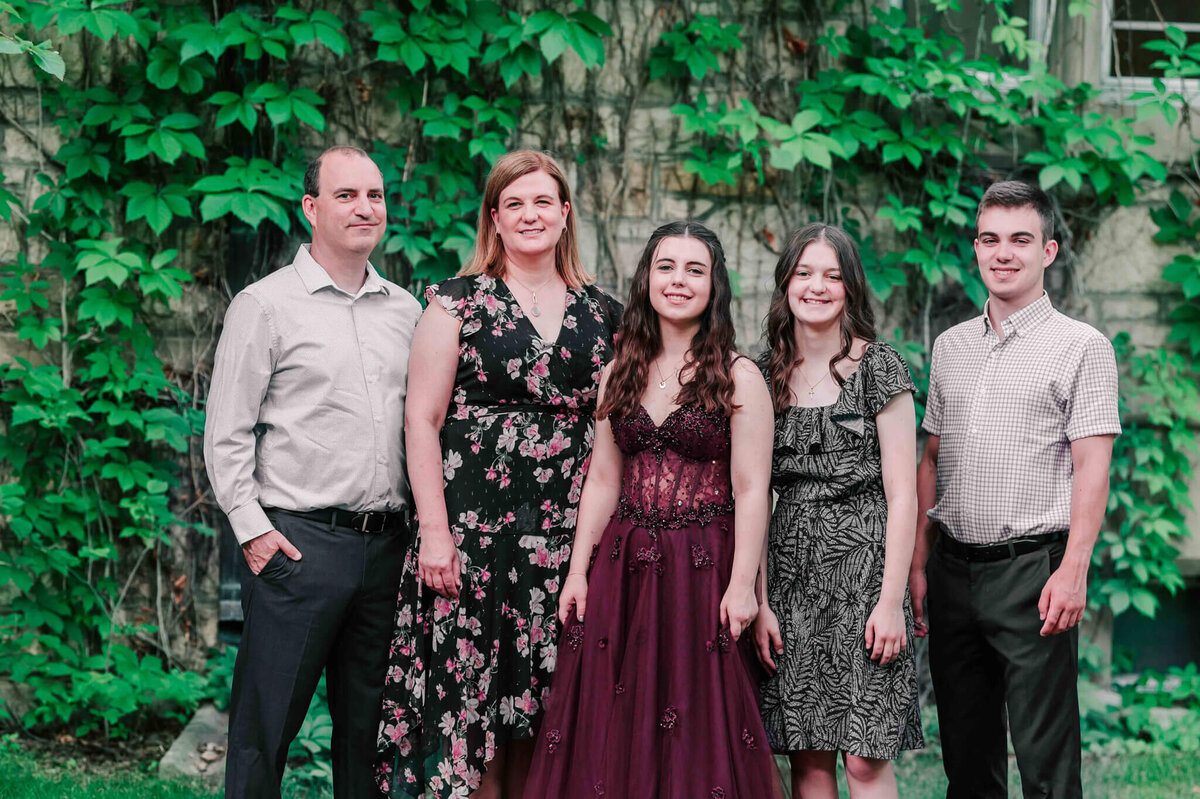 Highschool graduate standing with her family. 