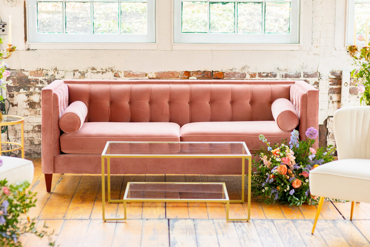 Pink velvet couch surroudned by flowers