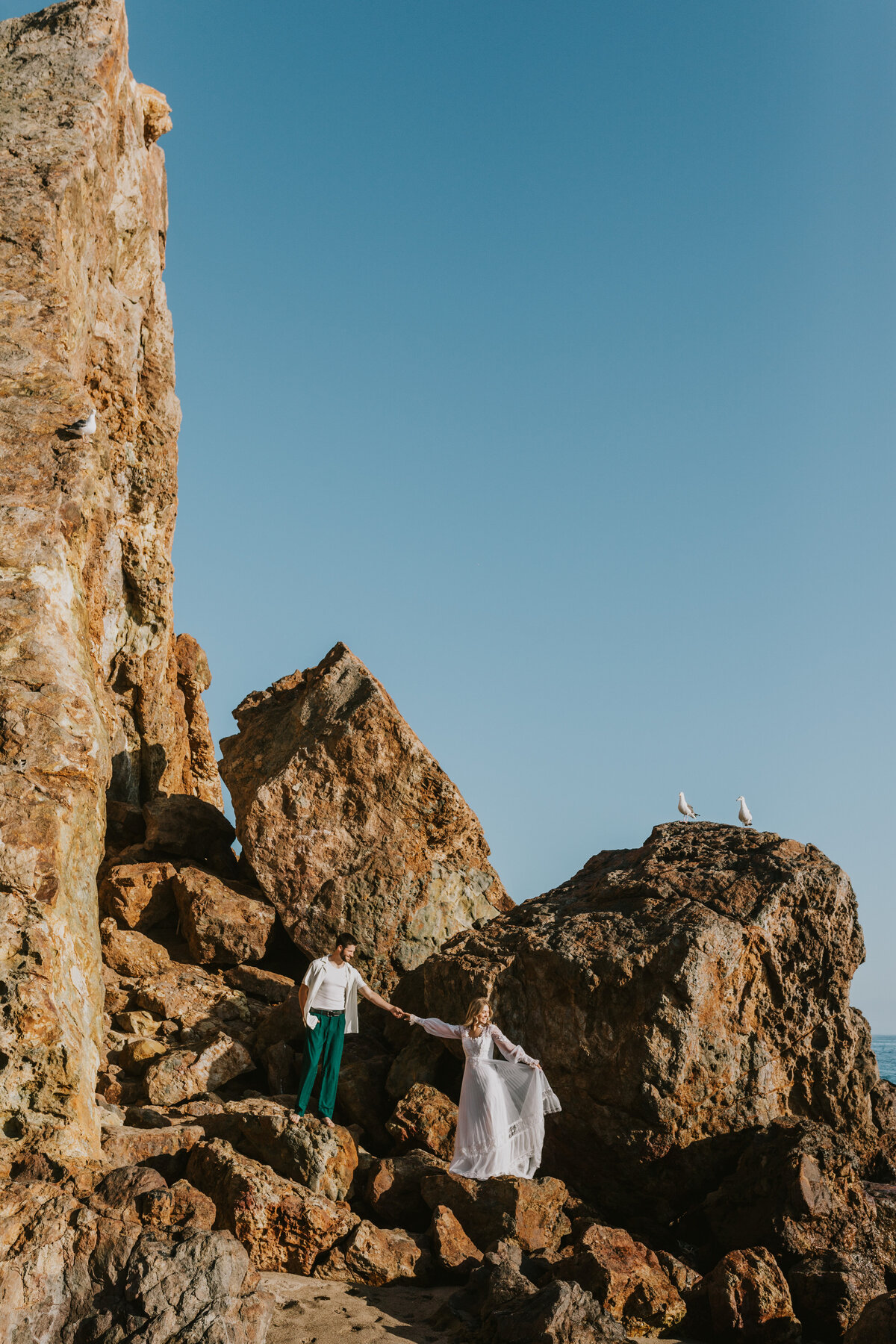 Candid embrace of a couple on a rocky coastline, destination engagement session.