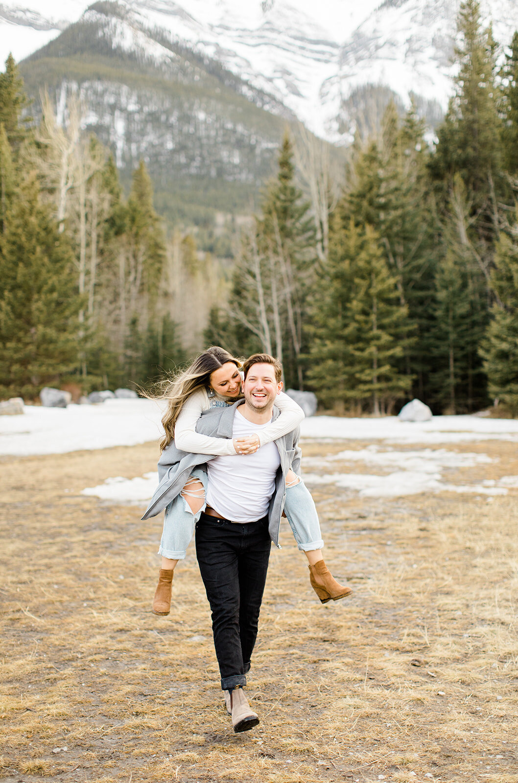 Man piggy-backing woman on his back in the Rocky Mountains near Calgary, AB.