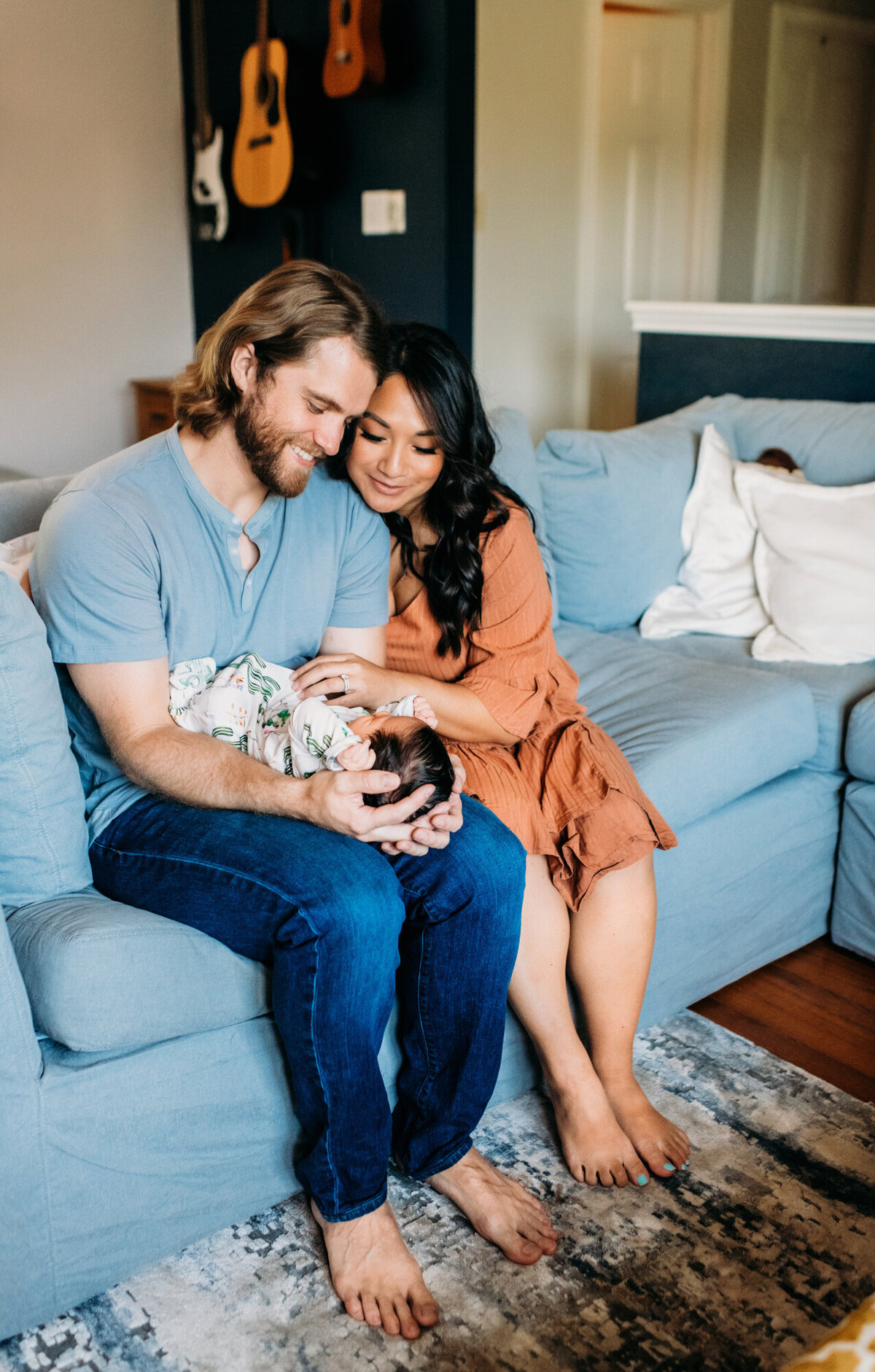 Newborn Photographer, Mom and Dad snuggling and looking down at baby girl.