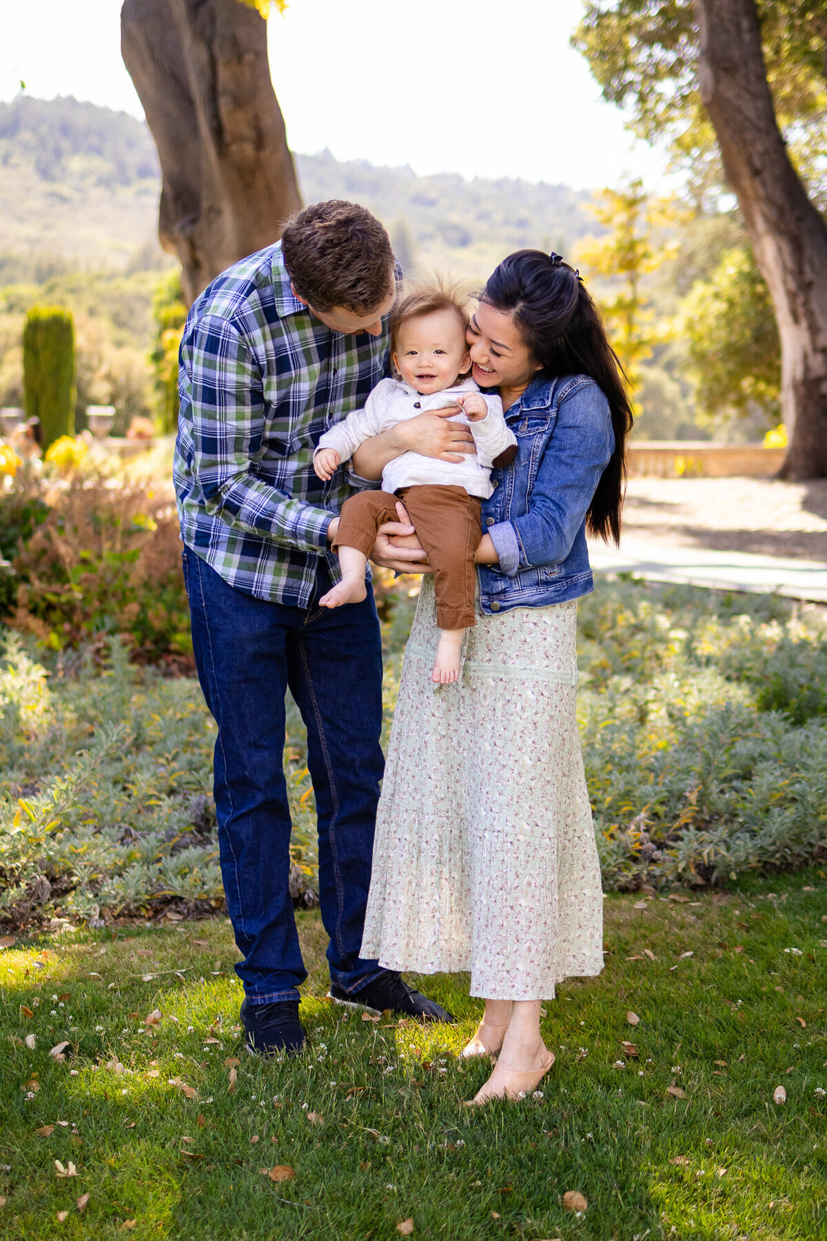 Parents kissing their baby boy during a golden-hour family photoshoot in the San Francisco Peninsula by San Francisco Peninsula family photographer 