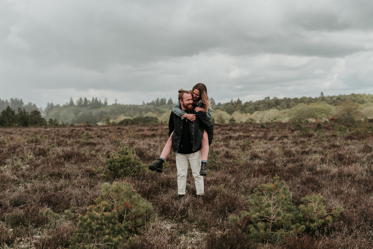 Couple piggyback ride in the stunning moorlands of Brockenhurst, New Forest