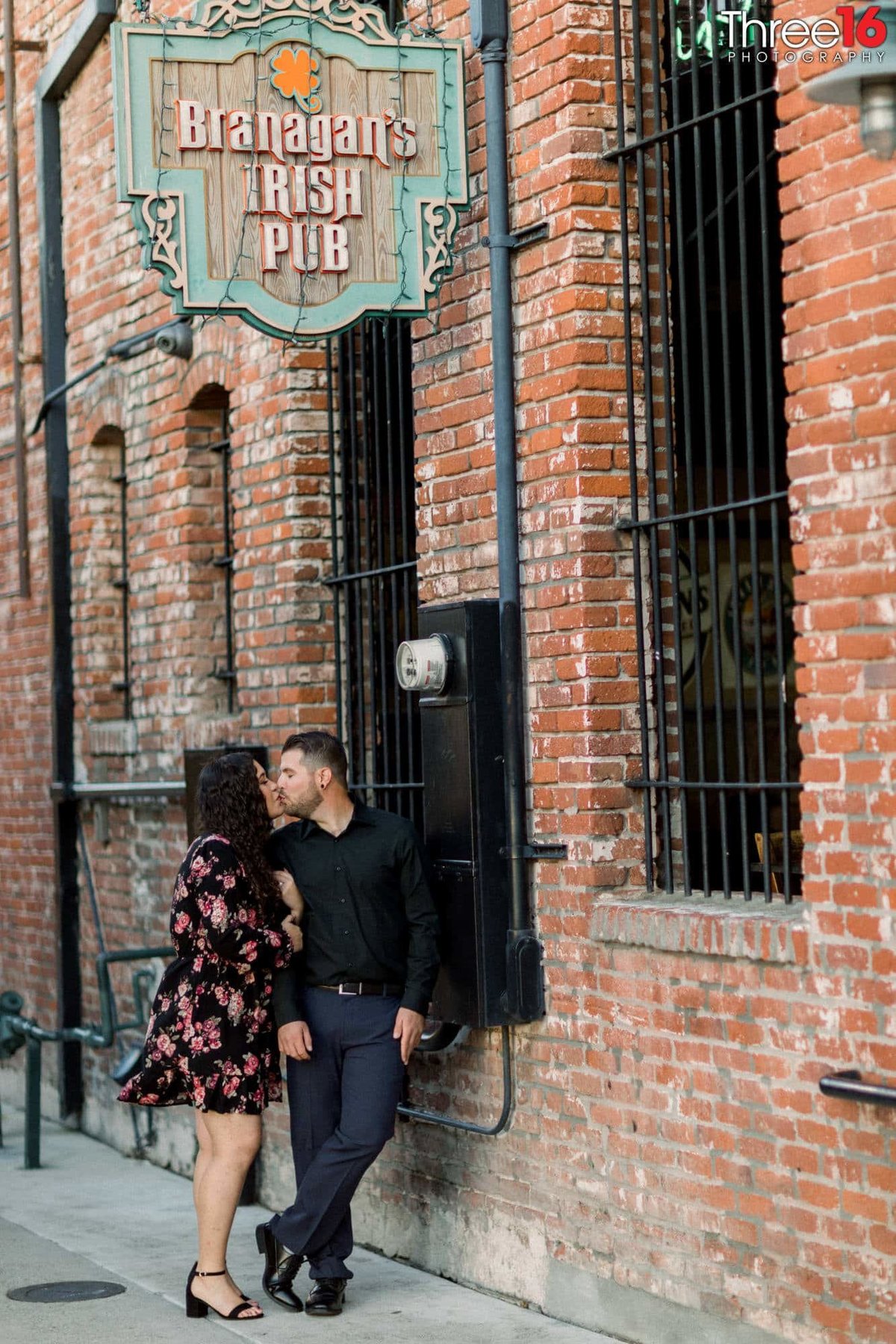 Engaged couple share a kiss in a back alley in Fullerton, CA