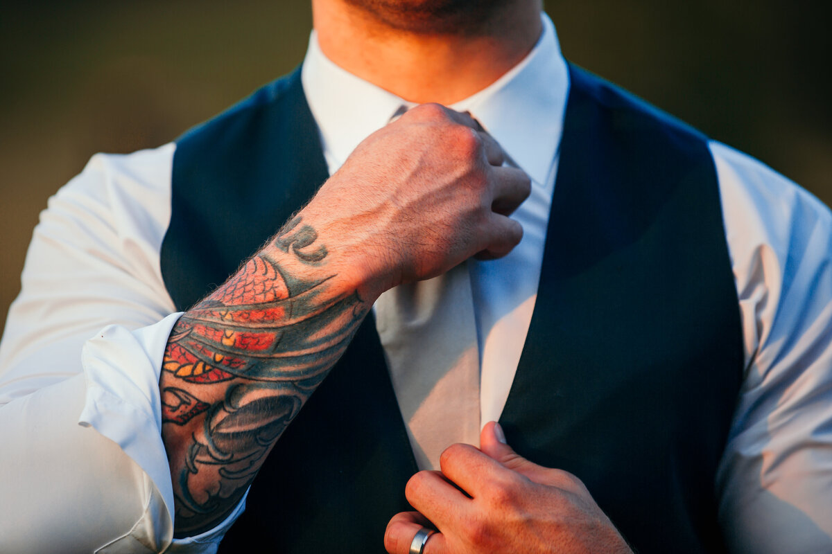 close up of groom adjust his tie