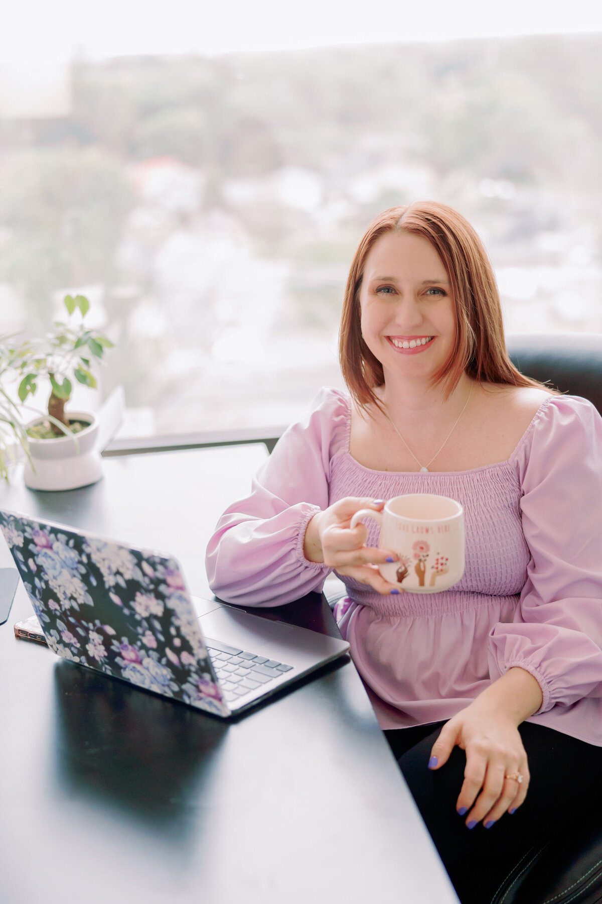 A person holds a mug while on their laptop.