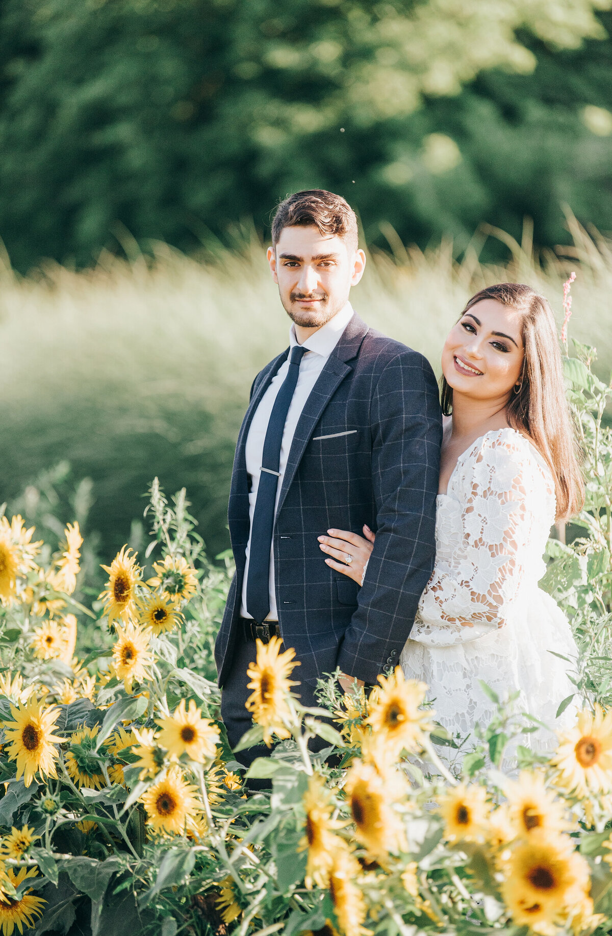Couple posing for engagement photos in  a whimsical sunflower field during their Summer engagement session