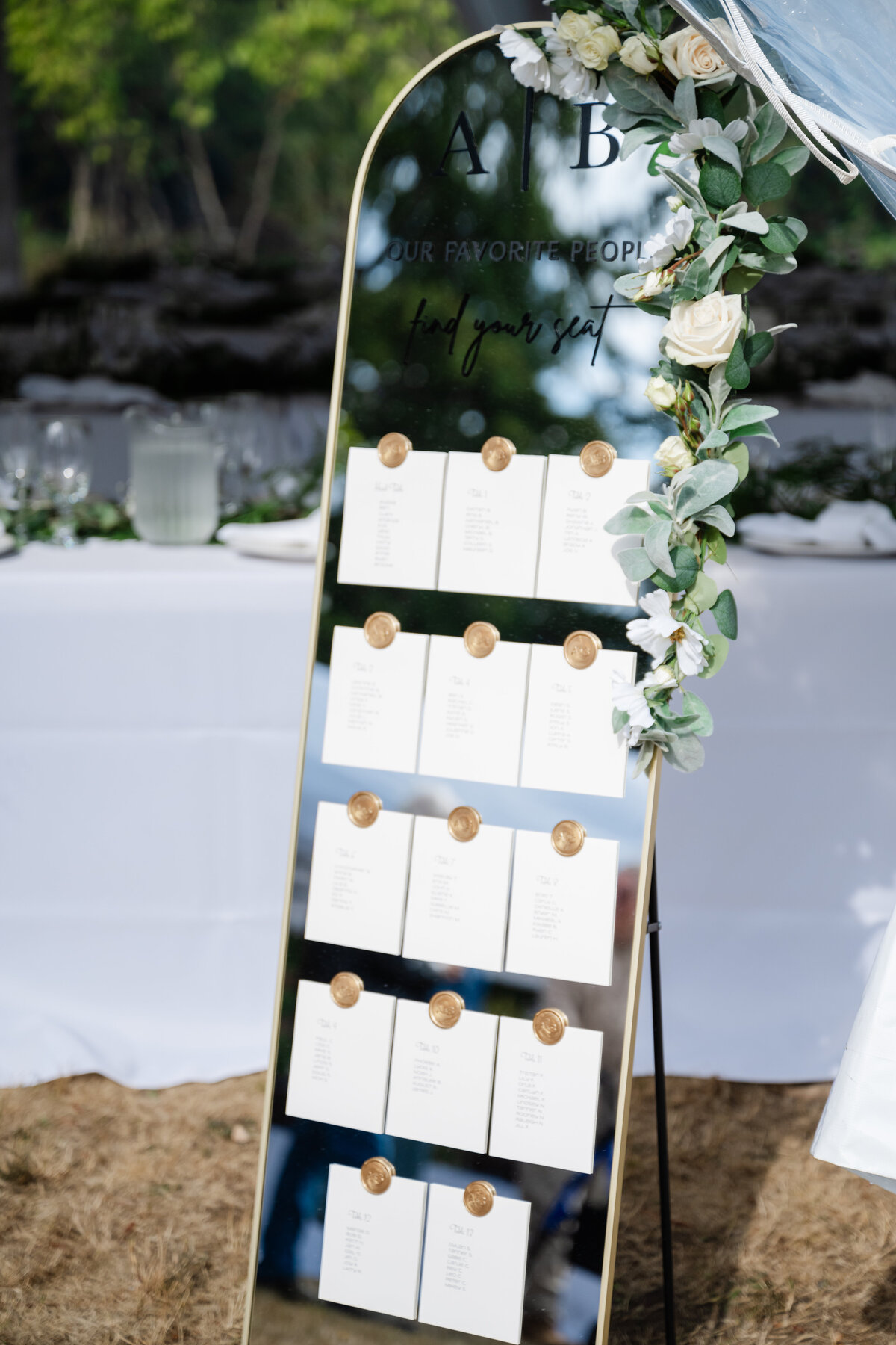 wedding seating chart posted on mirror with flowers